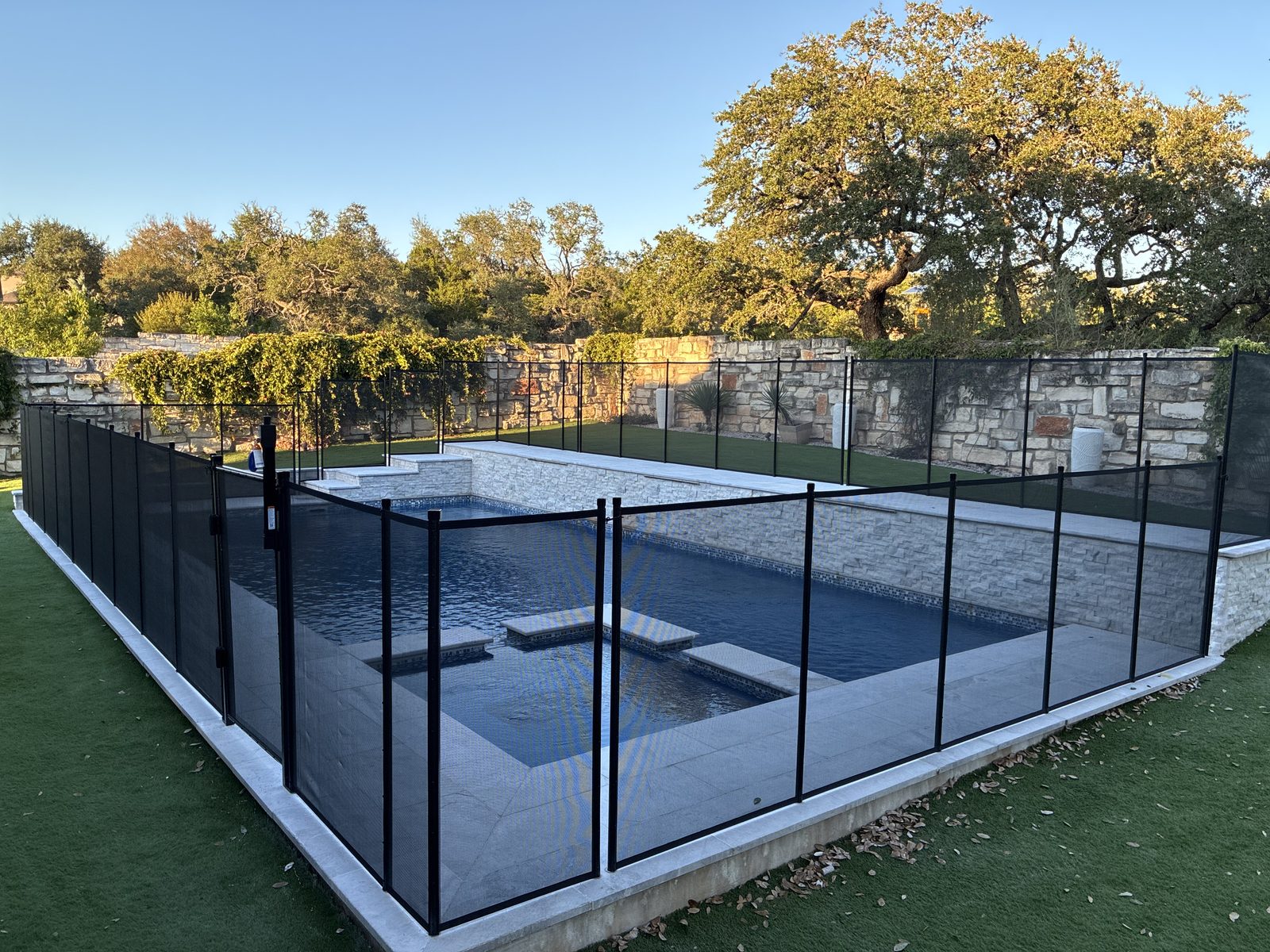 Removable mesh pool fence with a self-closing safety gate around a pool and spa in the Avana neighborhood of southwest Austin TX, All-Safe certified
