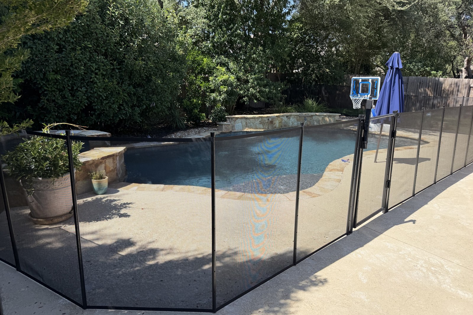Removable mesh pool fence with reinforced aluminum poles around a freeform pool in Cedar Park TX, All-Safe certified